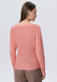 Sweter dzianinowy w kolorze koralowym o luźnym kroju, z długimi rękawami i szerokim dekoltem. Teksturowany materiał z luźną sylwetką.
