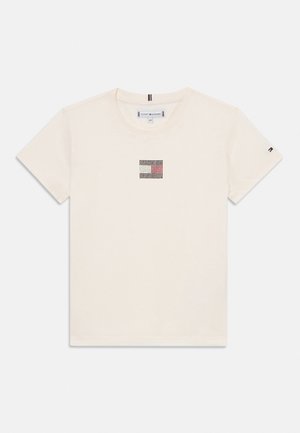 Majica s kratkim rukavima od kremaste pamučne tkanine s kvadratnim grafičkim uzorkom u crnoj, bijeloj i crvenoj boji na prsima. Ima rebrasti okrugli izrez.