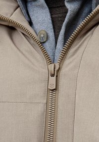 Bežna jakna z zadrgo, ki ima pod njo sivo plast z gumbi. Tkanina je gladka, oblikovanje pa vključuje kapuco.