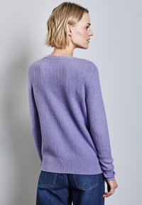 Lila Pullover mit gerippter Textur, langen Ärmeln und rundem Ausschnitt. Kombiniert mit blauen Jeans, von hinten angezeigt.