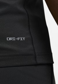 Camiseta deportiva DRI-FIT negra que presenta un tejido suave y elástico con costuras planas y un logo en blanco en el lado izquierdo.