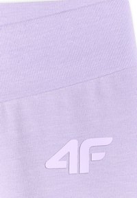 Gros plan sur un tissu violet clair avec une texture côtelée et un logo blanc "4F" imprimé dessus.