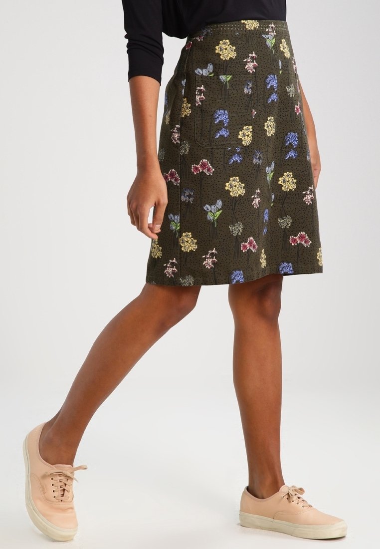 Falda de patrón floral en verde oscuro con flores amarillas, rosas y azules. Corte en A, de longitud hasta la rodilla, confeccionada en tejido texturizado.