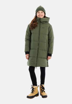 Grüne Pufferjacke mit hohem Kragen, Reißverschluss und schwarzen Akzenten, kombiniert mit einer passenden Strickmütze und braunen Winterstiefeln.