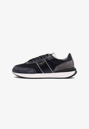 Schwarzer und grauer Sneaker aus Wildleder und synthetischen Materialien, mit einem weißen Streifen, runden Schnürsenkeln und einer strukturierten Gummisohle.