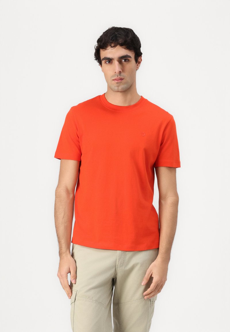Camiseta de algodón roja con cuello redondo y mangas cortas, que presenta un pequeño logo tonal en el pecho. Textura suave, diseño casual.