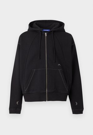 Schwarzer Zip-Hoodie mit Fronttaschen, Kordelzugkapuze, weißen Nähten und kleinem weißen Logo nahe der Tasche und den Ärmeln.