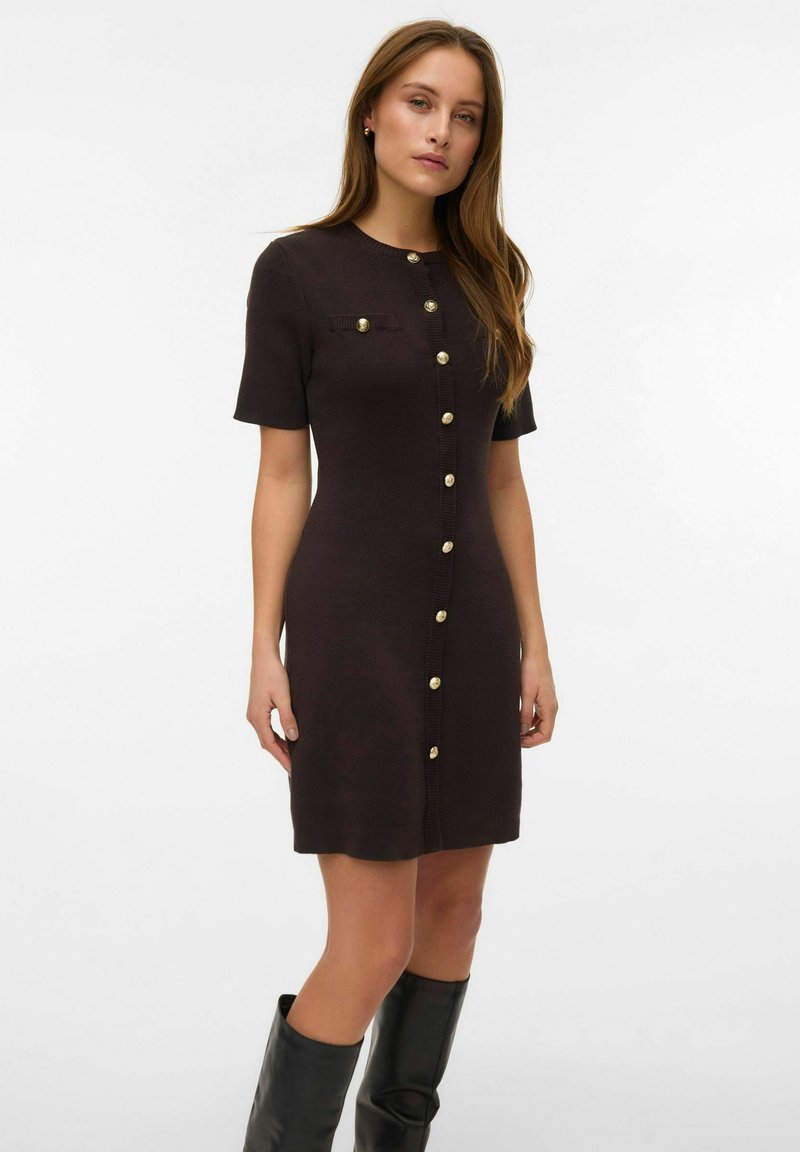 Abito di maglia marrone scuro con maniche corte, chiusura frontale con bottoni color oro e una piccola tasca applicata sul petto.