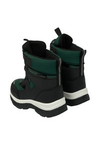 Musta ja vihreä vedenpitävä saapas, jossa on teksturoitu päällinen, pehmustettu kaulus ja paksu kumipohja, jossa on kulutuspintakuosi pidon takaamiseksi.