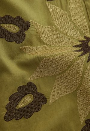 Kirjailtu kangas, jossa on vihreä tausta ja kullanvärisiä sekä tummanruskeita kukkakuoseja. Pinta on sileä ja yksityiskohtainen.