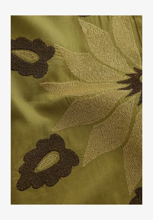 Broderet stof med en grøn baggrund, med gyldne og mørkebrune blomsterdesigns. Teksturen er glat med indviklede detaljer.