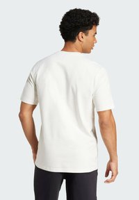 Hvid bomulds T-shirt med korte ærmer, rund hals og en glat tekstur, der har en afslappet pasform og et enkelt design bagpå.