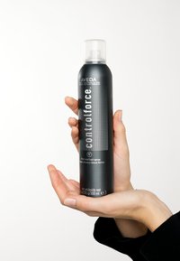 Aveda Control Force stevige hold haarspray in een zwarte fles met zilveren accenten, voorzien van een pompnuit en een rasterpatroon op het etiket.