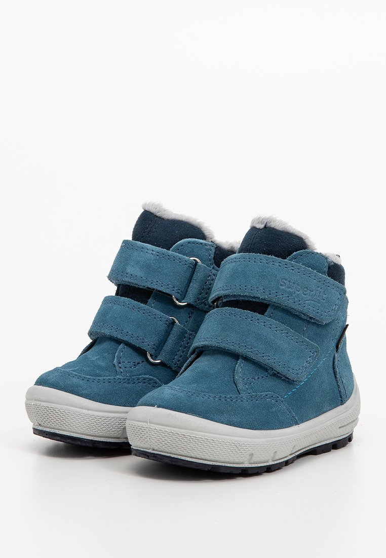 Blaue Wildleder-Stiefeletten mit zwei Klettverschlüssen und einem weißen Kunstpelz-Futter, ausgestattet mit einer grauen Gummisohle und einem abgerundeten Zehendesign.