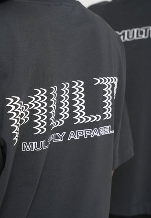 Schwarzes T-Shirt mit weißen Text "MULTI" in wellenförmigen Mustern und "MULTIPLY APPAREL" darunter. Kurze Ärmel und lässige Passform.