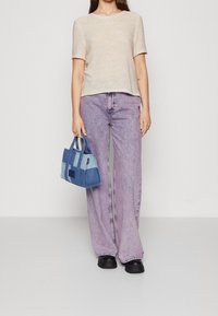 Lichtbeige gebreide top met korte mouwen, lavendel losse jeans en een blauwe handtas in meerdere tinten met gestructureerde handvatten. Glad textuur en casual ontwerp.