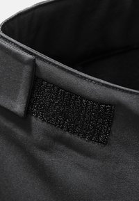 Sort stofkrave med en glat overflade, prydet med en sort Velcro-detalje på den ene side og en ren syet kant.