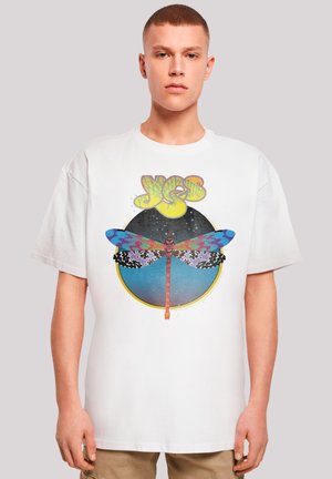 White graphic t-shirt featuring a colorful dragonfly design within a circular pattern, and the word "YES" in bold yellow letters above.