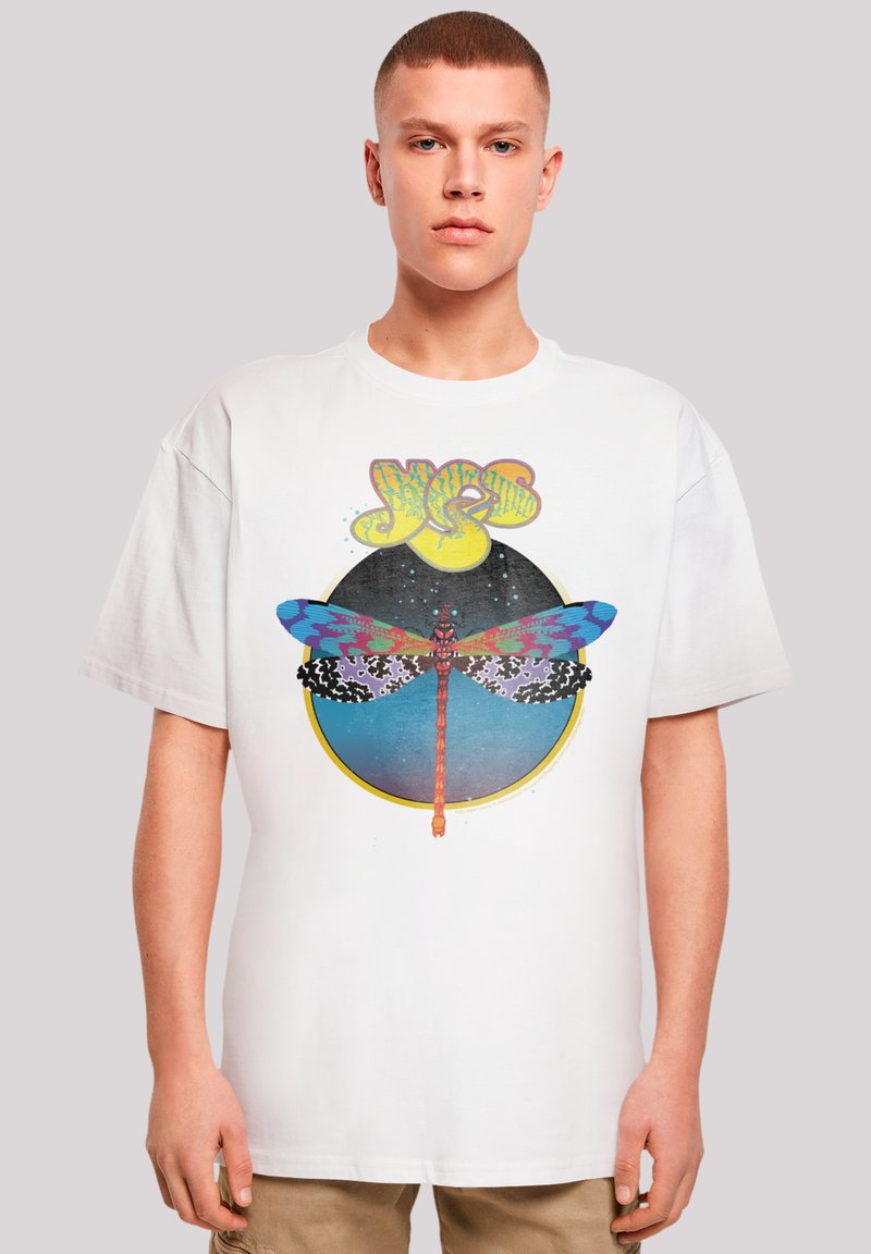 Weißes Grafik-T-Shirt mit einem bunten Libellen-Design innerhalb eines kreisförmigen Musters und dem Wort "JA" in fetten gelben Buchstaben darüber.