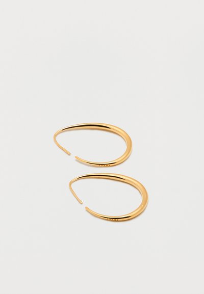 Ζευγάρι λεία, καμπύλα χρυσά σκουλαρίκια κρίκοι με λεπταίνει στις άκρες, τοποθετημένα σε απλό λευκό φόντο.