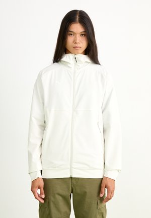 Giacca leggera color crema con zip frontale, colletto alto, polsini elasticizzati e due tasche laterali. Presenta dettagli del logo sottili.