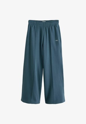 Wide-leg dark teal sweatpants with elastic waistband and "self." text on the upper left thigh.
