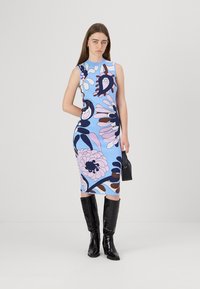 Αμάνικο φόρεμα bodycon με ανοιχτό μπλε βάση και τολμηρά floral σχέδια σε ροζ και σκούρο μωβ. Συνδυάζεται με λαμπερά μαύρα ψηλοτάκουνα μποτάκια.