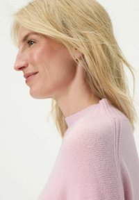 Hellrosa gestrickter Pullover mit hohem Hals, mit einem gerippten Muster und feinen Nähten an den Schultern. Glatte Oberfläche.