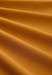 Textured fabric in a warm mustard yellow color, featuring pleats that create depth and smooth, soft surfaces with a fine weave.