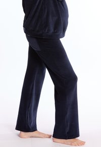 Marineblauwe, zachte velours broek met een rechte pijpdesign, voorzien van een comfortabele tailleband en subtiele achterzak. Gladde textuur.