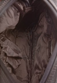 Interno di una borsa in tessuto nero con una texture liscia, numerosi scomparti e una cerniera. Foderato con materiale scuro e resistente.