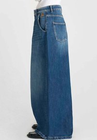 Falda de mezclilla, hasta los tobillos, de color azul oscuro, con una cintura alta, bolsillos laterales y un bolsillo trasero con solapa puntiaguda. Textura suave.