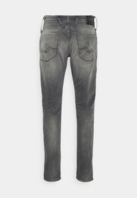 Jeans de denim gris con un corte ajustado, que cuentan con dos bolsillos traseros con detalles de costura geométrica y una cinturilla estándar.