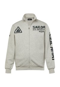 Sudadera con cremallera gris hecha de tela con puños acanalados. Presenta texto negro, logo de velero y acentos triangulares en el lado izquierdo y la manga.