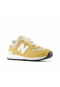 Zapatillas de ante amarillo y malla con detalles blancos, panel gris texturizado, cordones redondos y suela de goma negra. Presenta un prominente logo de 'N'.