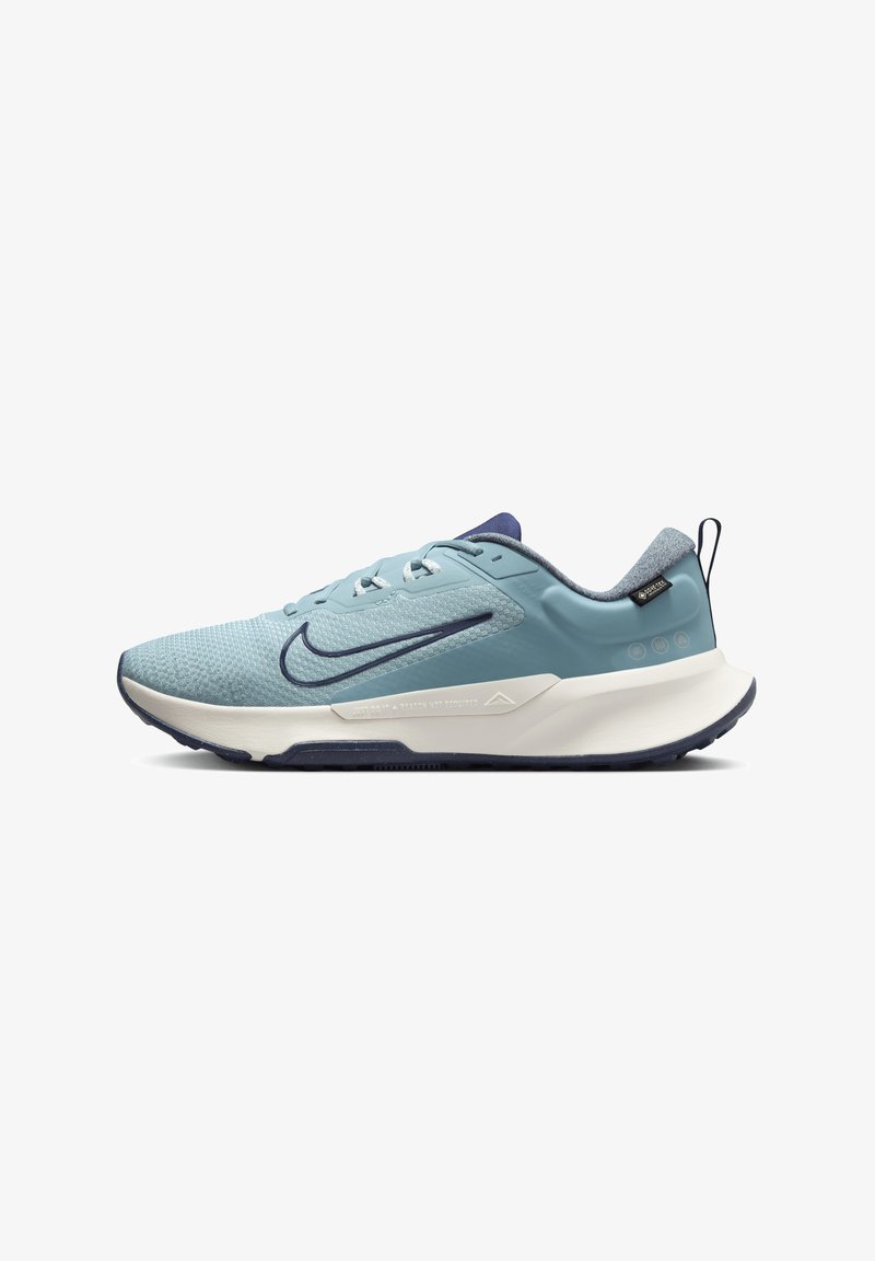Sapatilha desportiva azul clara com parte superior em malha, detalhes em azul marinho, sola branca, acabamento texturizado e detalhe do logo na lateral.