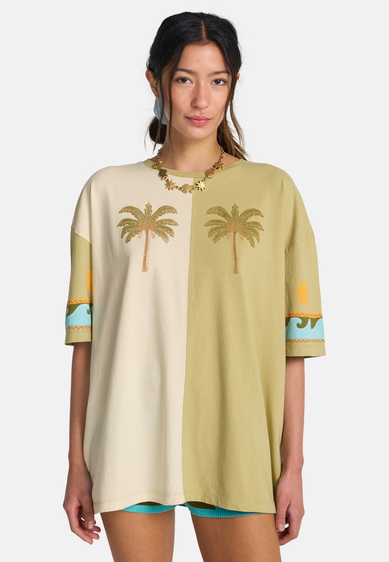 T-shirt oversize en coton avec sections divisées en beige et vert olive. Comprend une broderie de palmier et des accents décoratifs bleus et orange.