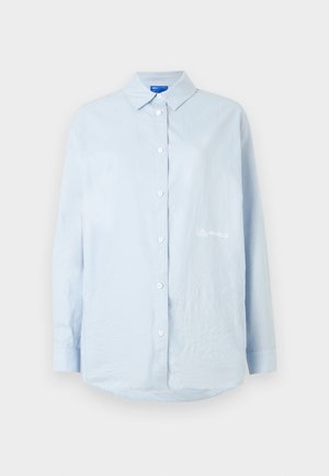 Vaaleansininen pitkähihainen kauluksellinen nappipaita, jossa valkoiset napit ja vasemmassa rinnassa pieni valkoinen "Karl Lagerfeld Jeans" -logo.