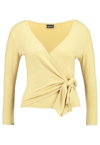 Gelbes Langarmshirt mit tiefem V-Ausschnitt und einer gebundenen Knotendetail an der Taille. Hergestellt aus weichem Stoff mit glatter Textur.
