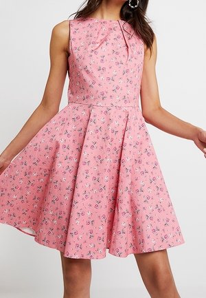 Ärmelloses rosa Kleid mit kleinem Blumenmuster, tailliertem Bund und ausgestelltem Rock, getragen von einer Frau mit offenem Haar und Creolen.