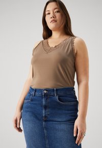 Brun topp med blondedetaljer ved halsen, kombinert med høyde middels blå denimskjørt med frontlommer og knappelukking.