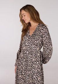 Luipaardprint wikkeljurk met lange mouwen, V-hals en een tailleband. Gemaakt van lichtgewicht stof met een zachte textuur in beige en zwarte tinten.