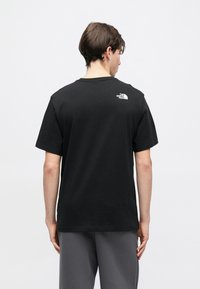 Μαύρο βαμβακερό μπλουζάκι με μικρό λευκό λογότυπο στο πάνω μέρος της πλάτης, στρογγυλή λαιμόκοψη και κοντά μανίκια. Λείες, άνετη εφαρμογή.