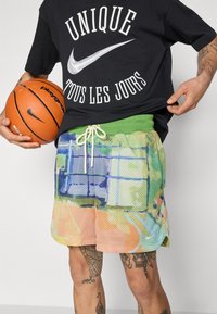 Multifarvede mesh basketball shorts med en grøn elastisk talje og hvid snøre. Har abstrakte mønstre i blå, orange og grøn.