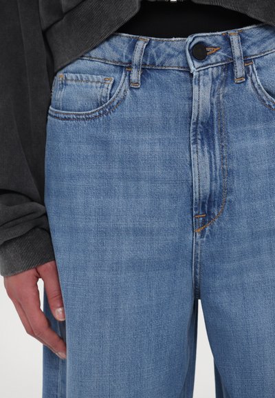 Hellblaue Jeans aus Denim mit hoher Taille, fünf Taschen und dezenten Nähten. Der Stoff hat eine glatte Textur und einen leichten Verblassungsgrad.