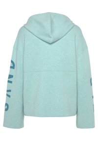 Hellblauer Kapuzenpullover mit herunterhängenden Schultern, großen Ärmeln und dem Wort "SANDY" in Dunkelblau auf dem linken Ärmel gedruckt.