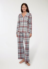 Set di pigiama a quadri in grigio, rosso e blu. Maglia a maniche lunghe con bottoni e colletto, pantaloni abbinati morbidi e larghi. Texture del tessuto morbida.