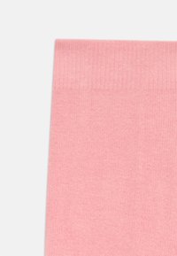 Tissu tricoté rose avec un motif côtelé sur le bord supérieur, présenté sur un fond blanc.