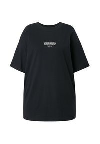 Sort oversized T-shirt lavet af bomuld, med rund hals og korte ærmer. Tekst på forsiden i hvid: "JEG KLÆDER MIG FOR KOMPLIMENTER..."
