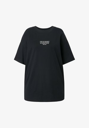T-shirt noir surdimensionné en coton, avec un col rond et des manches courtes. Texte sur le devant en blanc : "JE M'HABILLE POUR LES COMPLIMENTS..."
